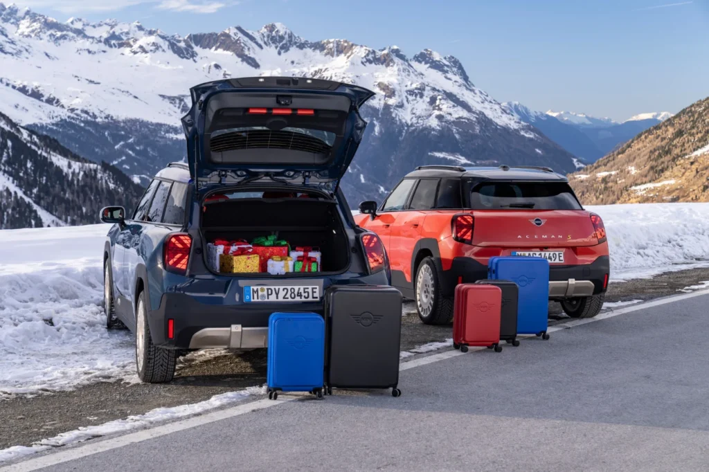 MINI na zimowym wyjeździe w górach, otwarty bagażnik i walizki jako akcesoria podróżne MINI