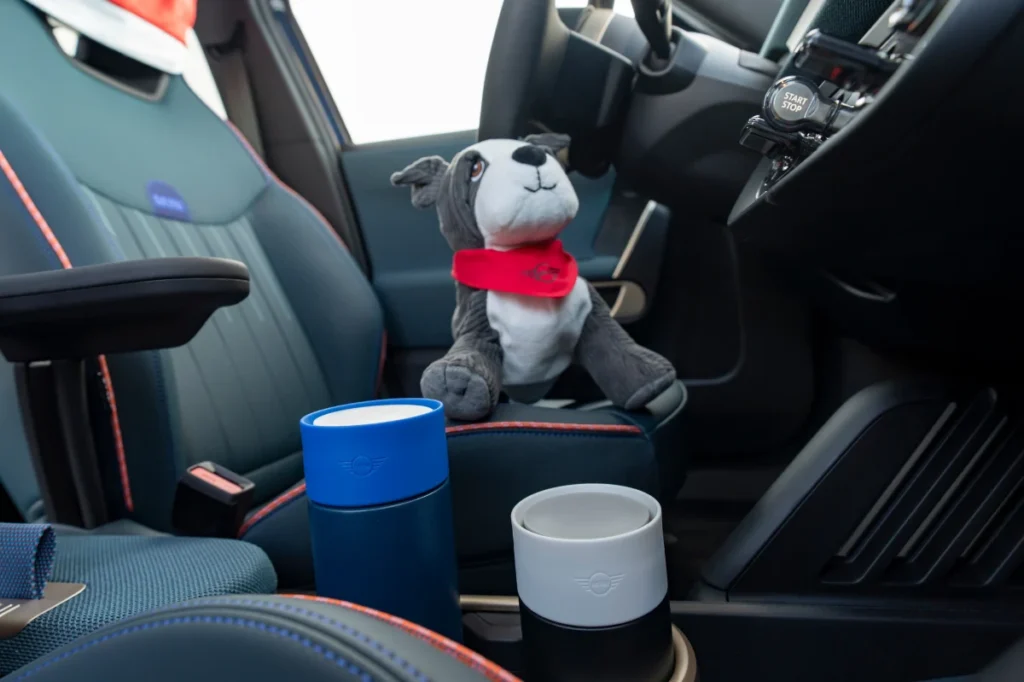 Wnętrze MINI z akcesoriami, kubki termiczne MINI i pluszowa maskotka na fotelu pasażera