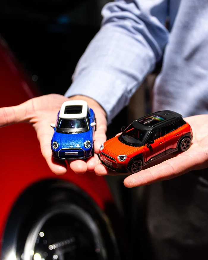 Miniatury samochodów MINI trzymane w dłoniach, akcesoria MINI Lifestyle, pomysł na prezent
