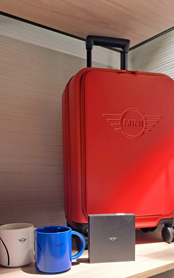 Czerwona walizka MINI na półce, kubki MINI i akcesoria MINI Lifestyle, pomysł na prezent