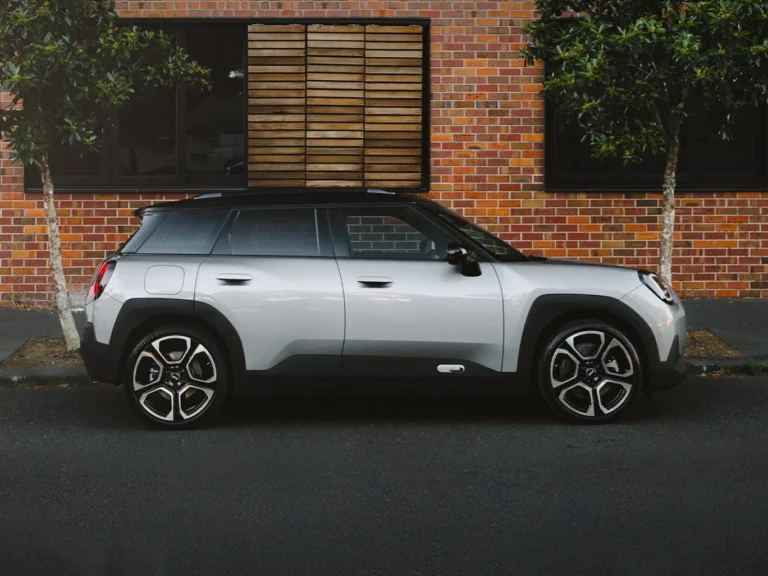 Srebrny MINI Aceman, ujęcie z boku, zaparkowany przy ceglanej ścianie w miejskiej scenerii