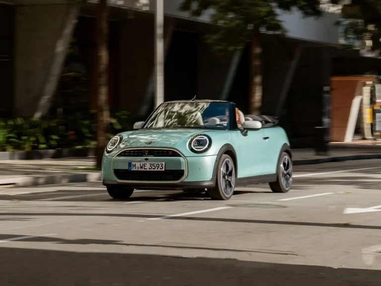 Miętowy MINI Cooper Cabrio jadący po mieście z otwartym dachem, ujęcie z przodu