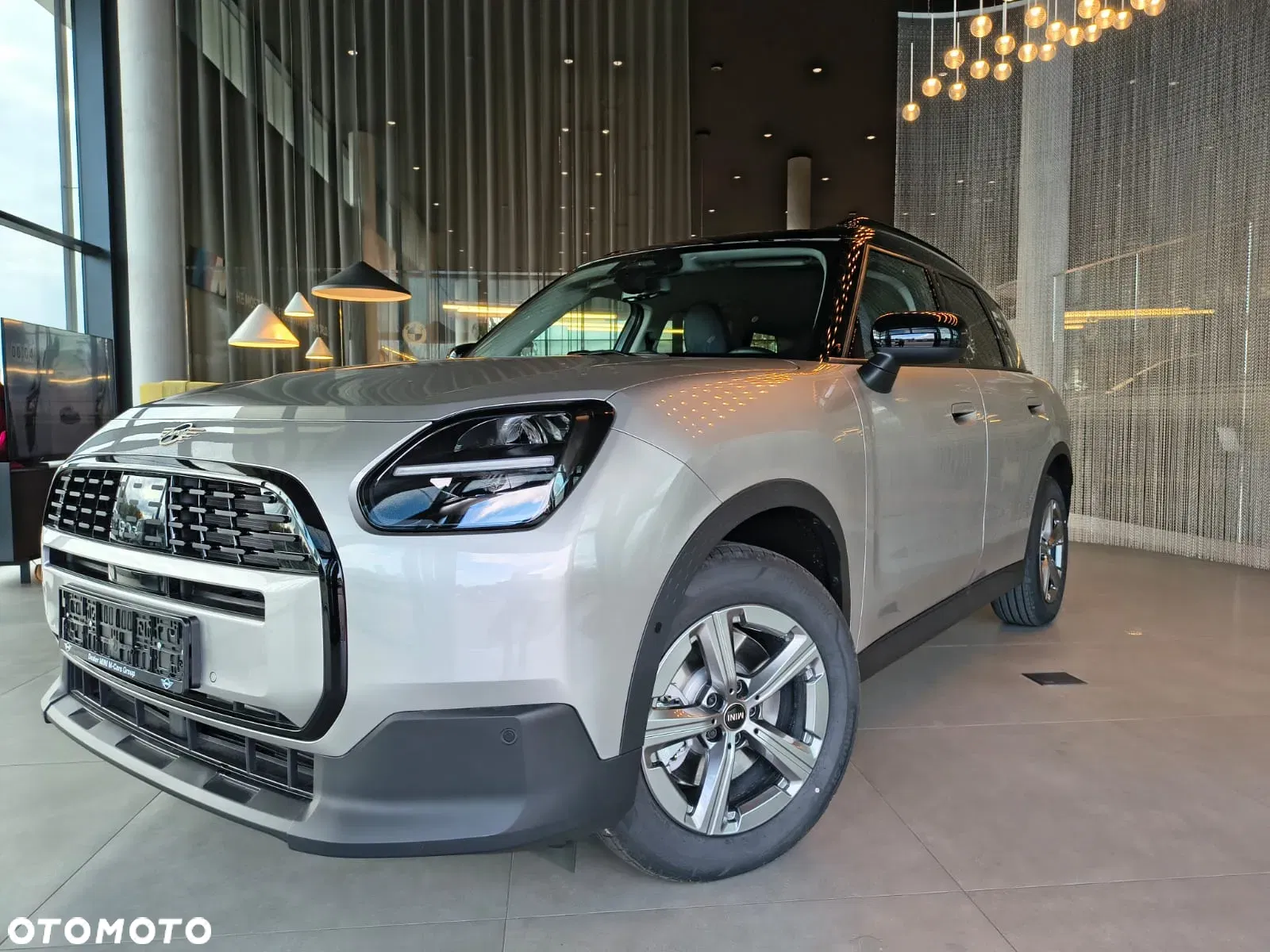 Jasne MINI Countryman w salonie, ujęcie przód-bok, przestronna strefa lounge w tle. Samochody MINI Kraków, Małopolska