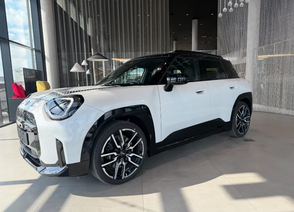 Jasne MINI Countryman w salonie, ujęcie przód-bok, przestronna strefa lounge w tle. Samochody MINI Kraków, Małopolska