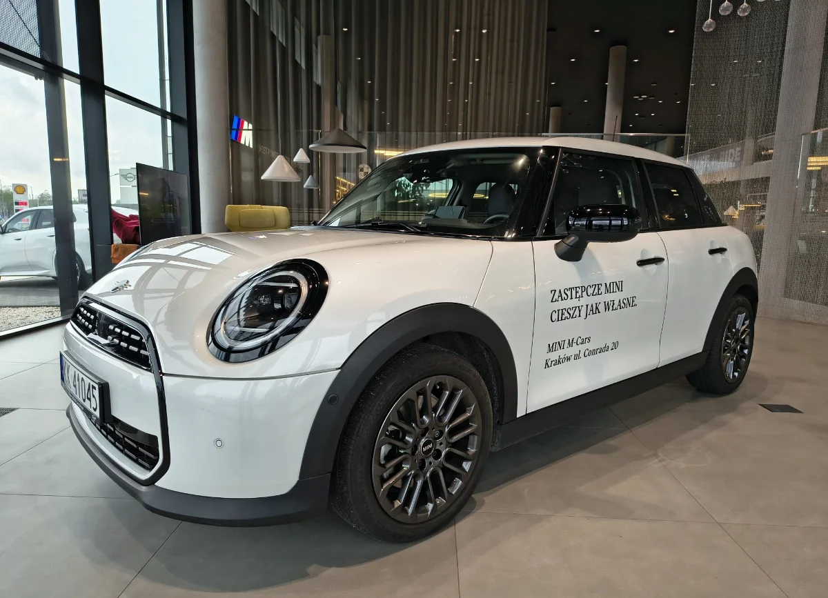 Jasne MINI Countryman w salonie, ujęcie przód-bok, przestronna strefa lounge w tle. Samochody MINI Kraków, Małopolska