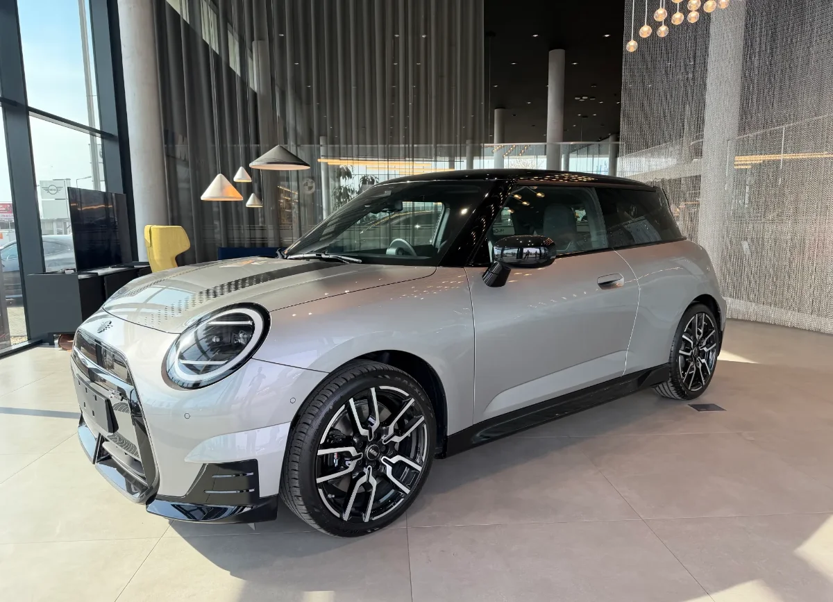 Jasne MINI Countryman w salonie, ujęcie przód-bok, przestronna strefa lounge w tle. Samochody MINI Kraków, Małopolska