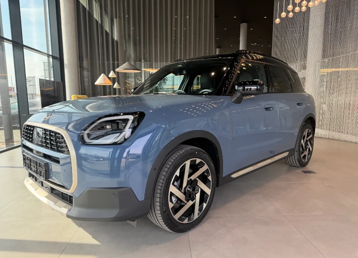 Jasne MINI Countryman w salonie, ujęcie przód-bok, przestronna strefa lounge w tle. Samochody MINI Kraków, Małopolska