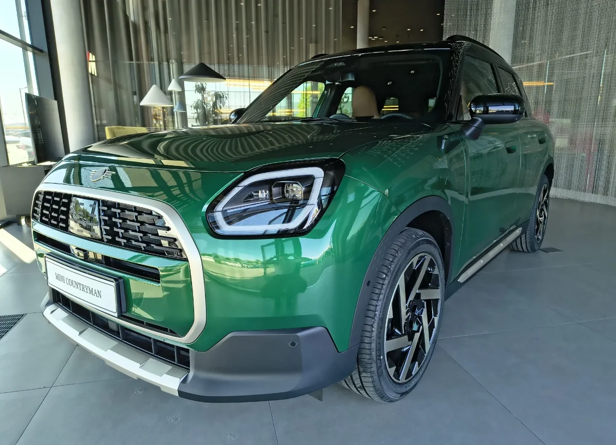 Jasne MINI Countryman w salonie, ujęcie przód-bok, przestronna strefa lounge w tle. Samochody MINI Kraków, Małopolska