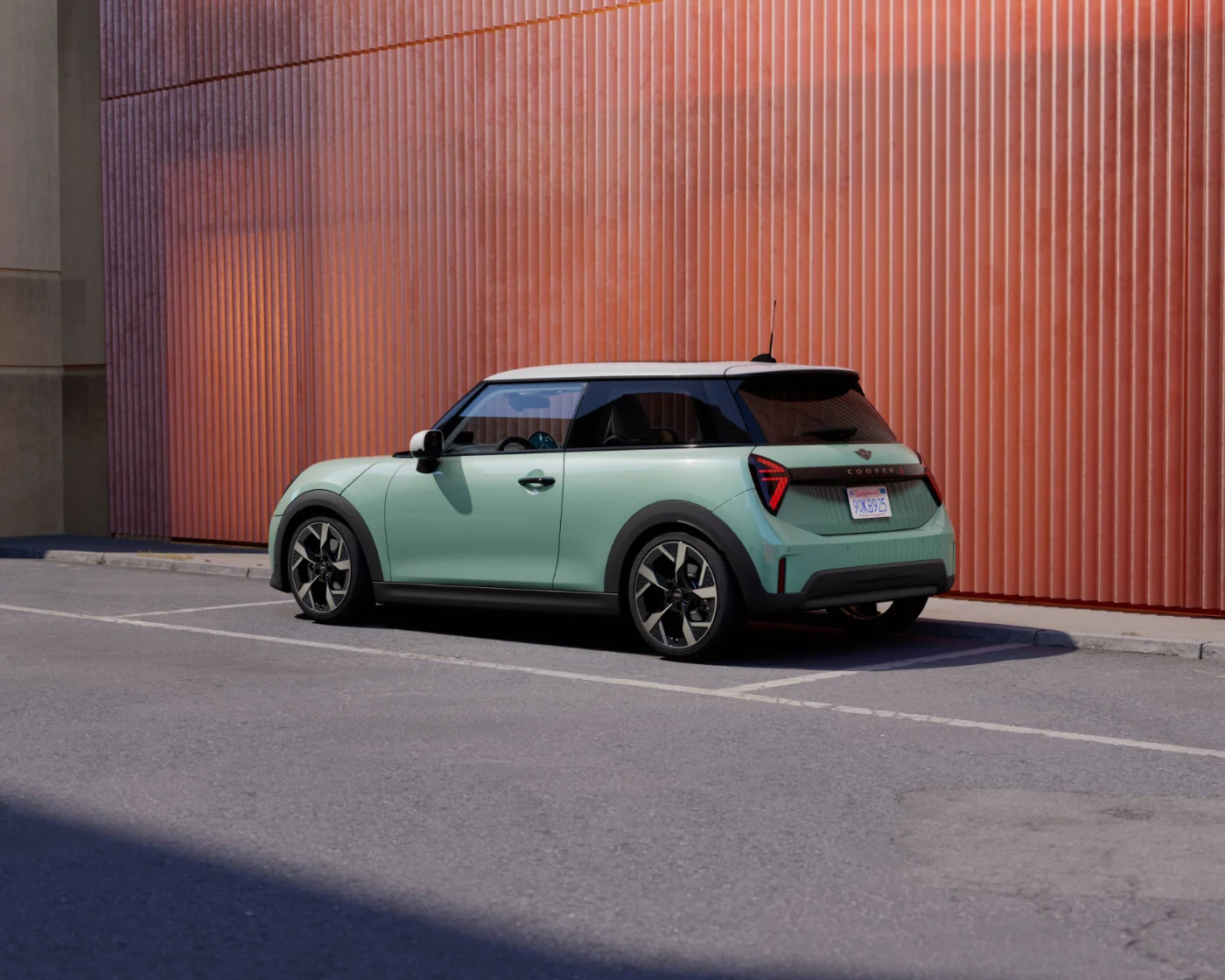 Nowe MINI Cooper ONE F66 w kolorze miętowym zaparkowane przy nowoczesnej elewacji budynku. Miejski design i kompaktowe nadwozie MINI.
