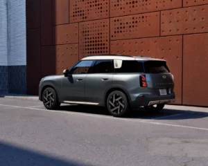 Nowe MINI Countryman ONE od tyłu na tle nowoczesnej architektury. Charakterystyczne lampy LED i przestronne nadwozie SUV.